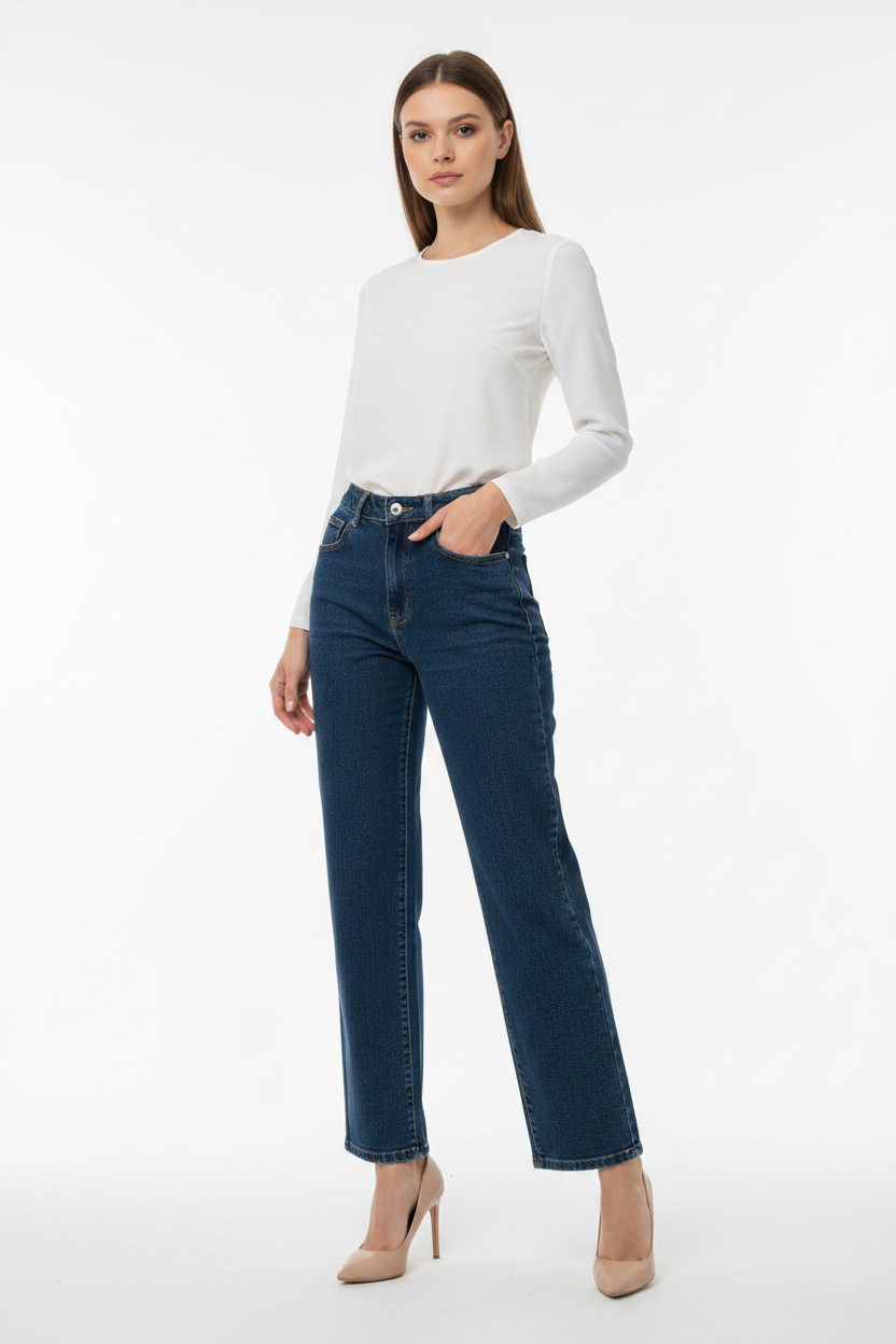 Model in donkerblauwe straight-leg jeans Miss Bon met witte blouse en nude hakken