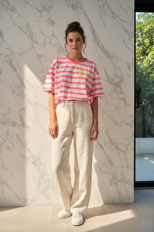 Model draagt de roze gestreepte Top Timiami met gele Soleil tekst in een zomerse editorial setting