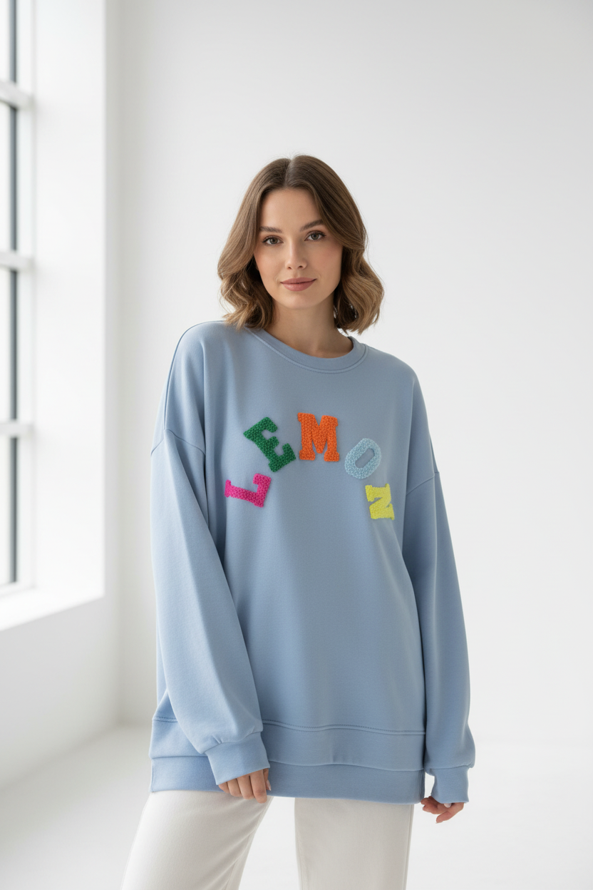 Model draagt lichtblauwe oversized Lemon sweater met kleurrijke fluffy letters