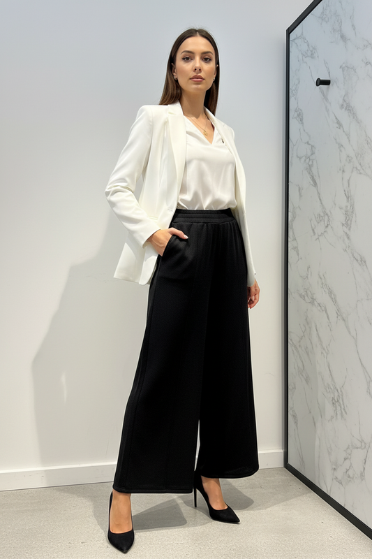 Model draagt de zwarte geklede wide-leg Broek C&S met getextureerde stof in een luxe editorial setting