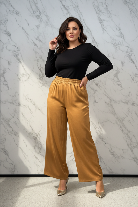 Model draagt de okergele plus size satijn wide-leg Broek Times in een luxe editorial setting