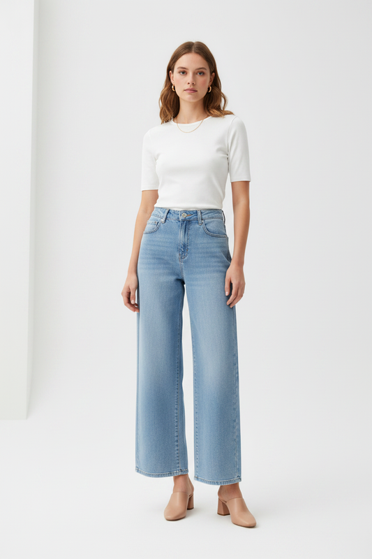 Model in lichtblauwe wide-leg jeans Goodies met wit topje en nude mules