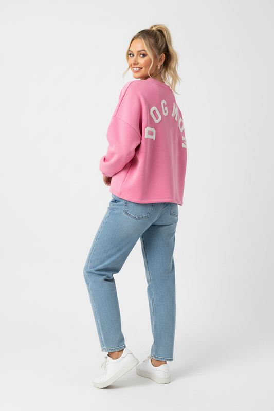 Model draagt het DOGMOM Oversized Sweatshirt in roze met wit geborduurd logo op de rug