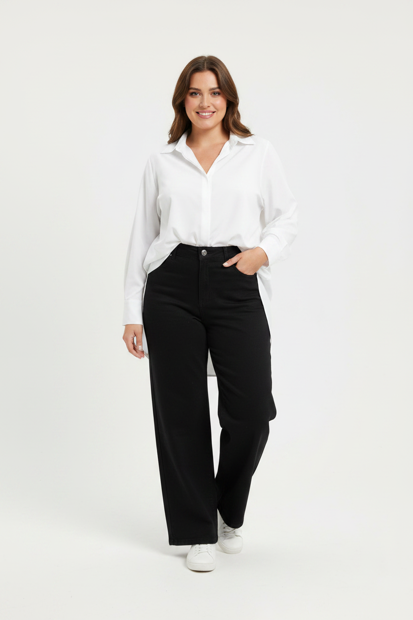 Plus-size model in zwarte wide-leg jeans Goodies met witte blouse en sneakers