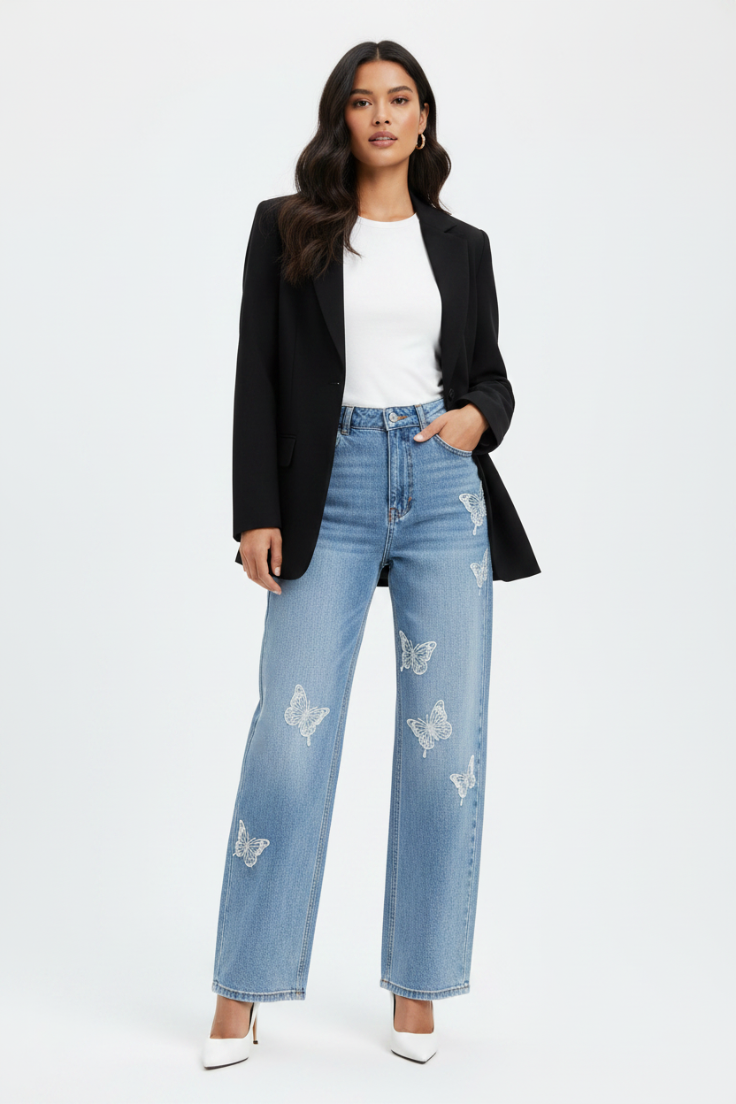 Model in lichtblauwe wide-leg jeans Miss Bon met vlinderborduurwerk, wit topje en zwarte blazer