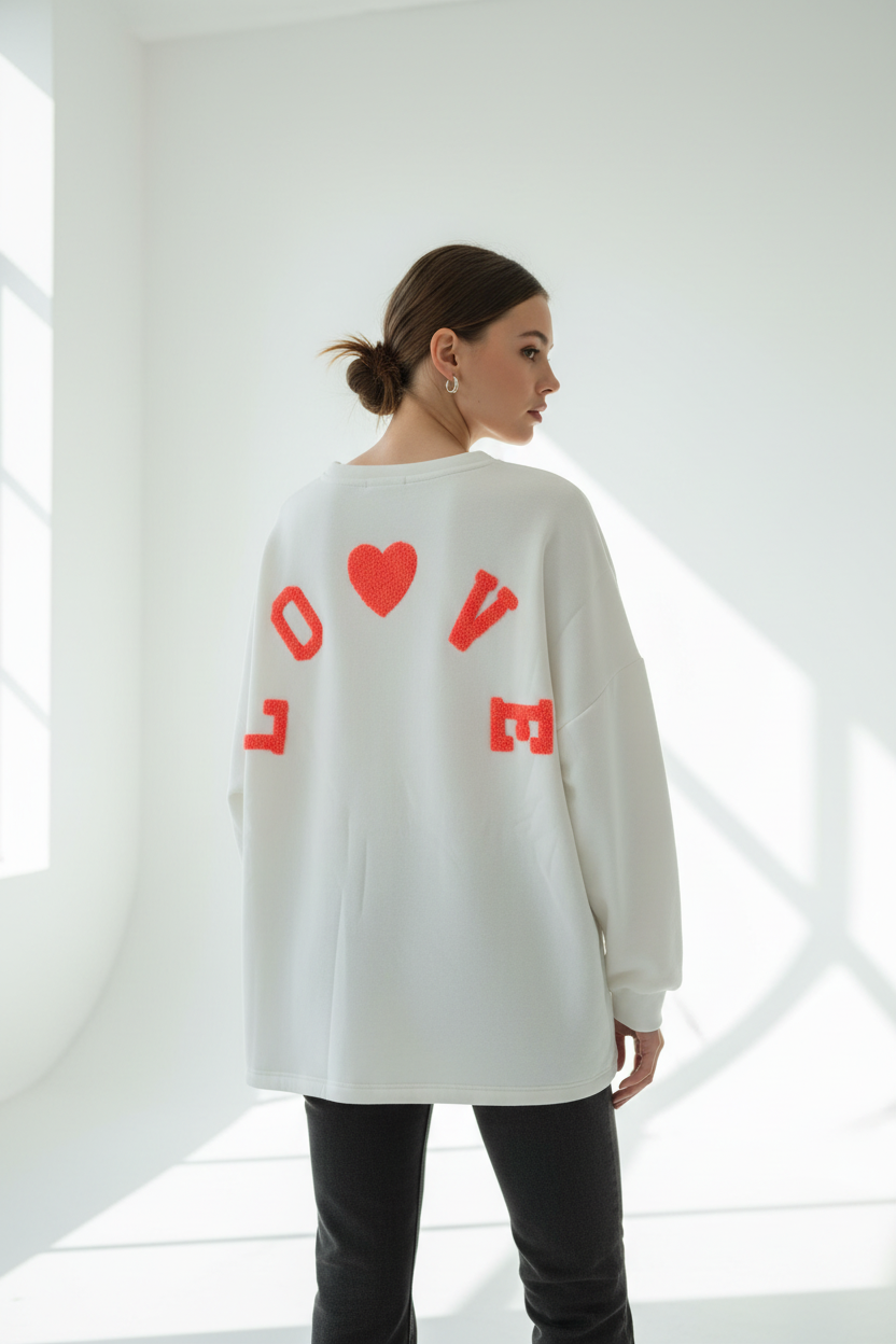 Model draagt witte oversized LOVE sweatshirt met rode fluffy letters op de rug