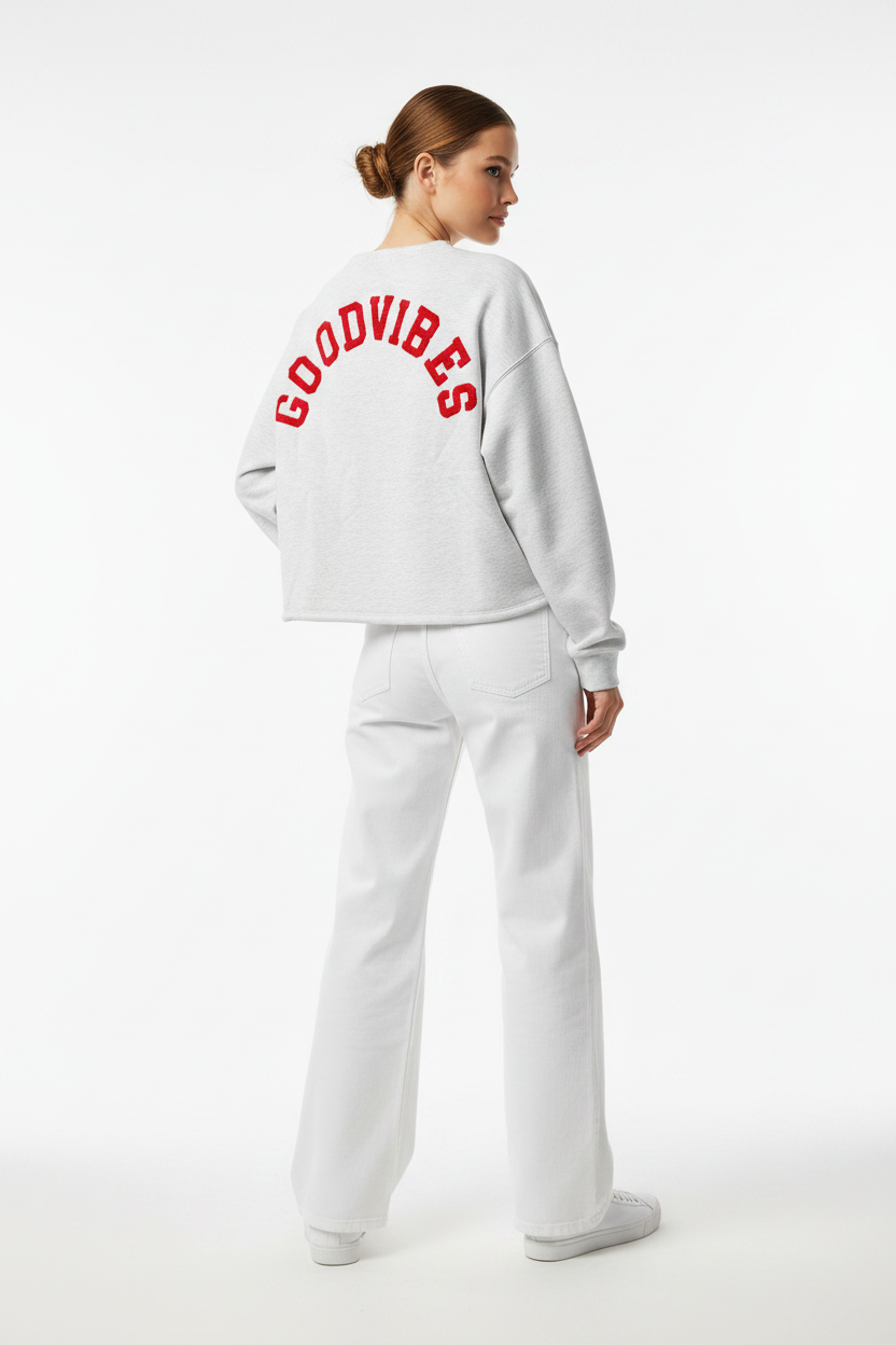 Model draagt het GOODVIBES Oversized Sweatshirt in grijs melange met rood geborduurd logo op de rug