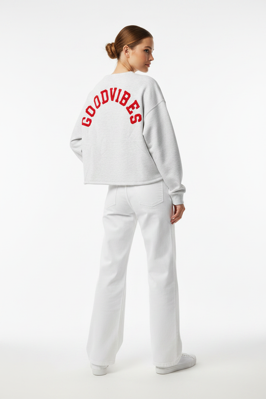 Model draagt het GOODVIBES Oversized Sweatshirt in grijs melange met rood geborduurd logo op de rug