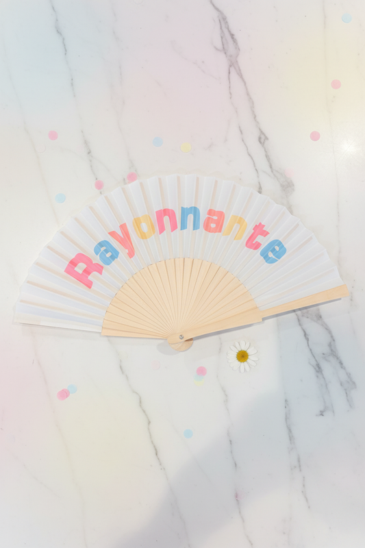 Witte zomerwaaier Rayonnante met vrolijke roze en blauwe letters en bamboe handvat