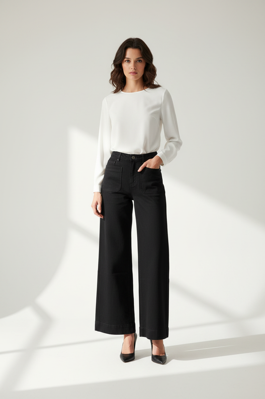 Model in zwarte wide-leg jeans C&S, gestileerd met witte blouse en zwarte hakken