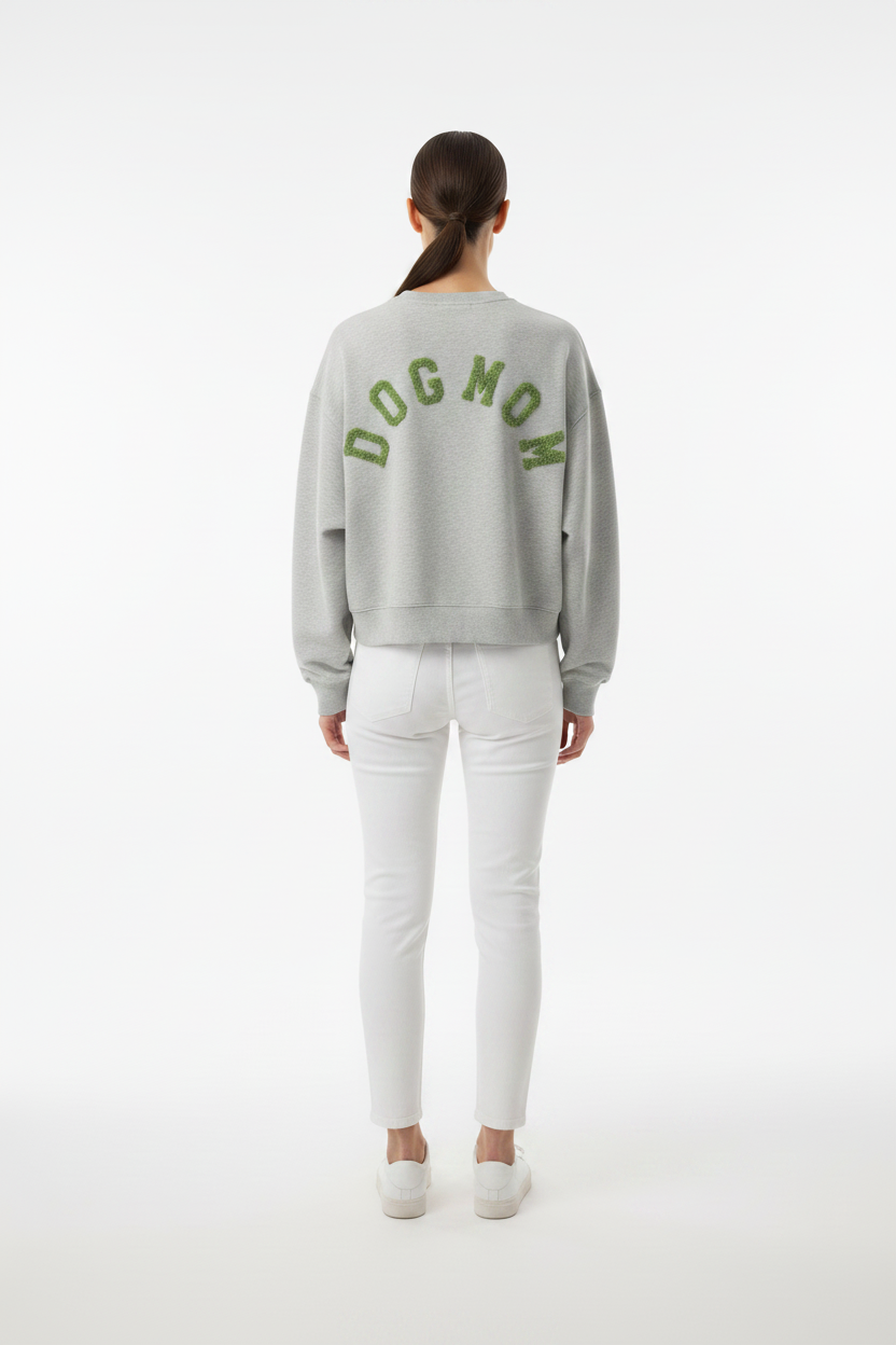 Model draagt het DOGMOM Oversized Sweatshirt in grijs melange met groen geborduurd logo op de rug