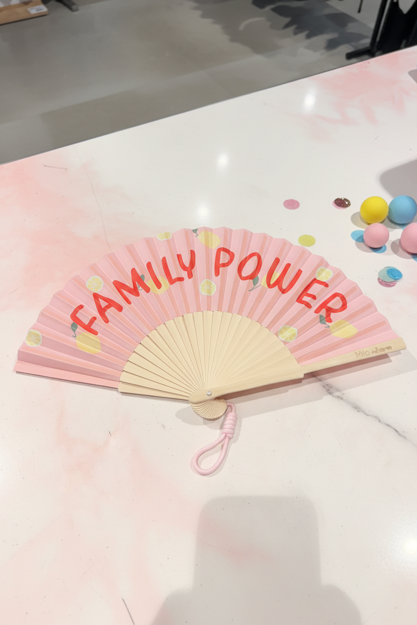 Roze waaier Family Power met gele ballonnetjes en rode tekst en bamboe handvat met roze koordje