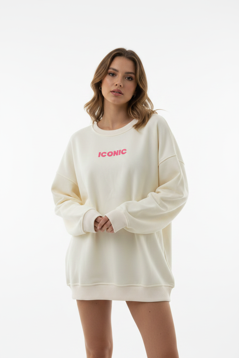 Model draagt crème oversized sweater met roze ICONIC logo