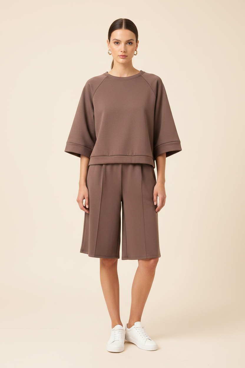 Model draagt taupe tweedelige set met sweater en shorts